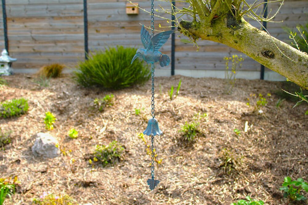 Décoration de jardin suspendue représentant un oiseau avec une clochette accrochée à un arbre